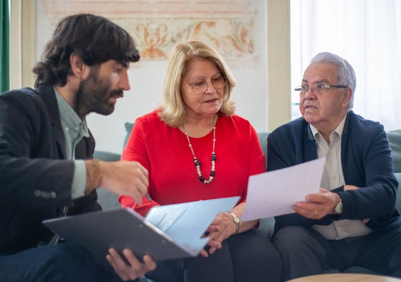 A man going over papers with an older couple on a sofa
