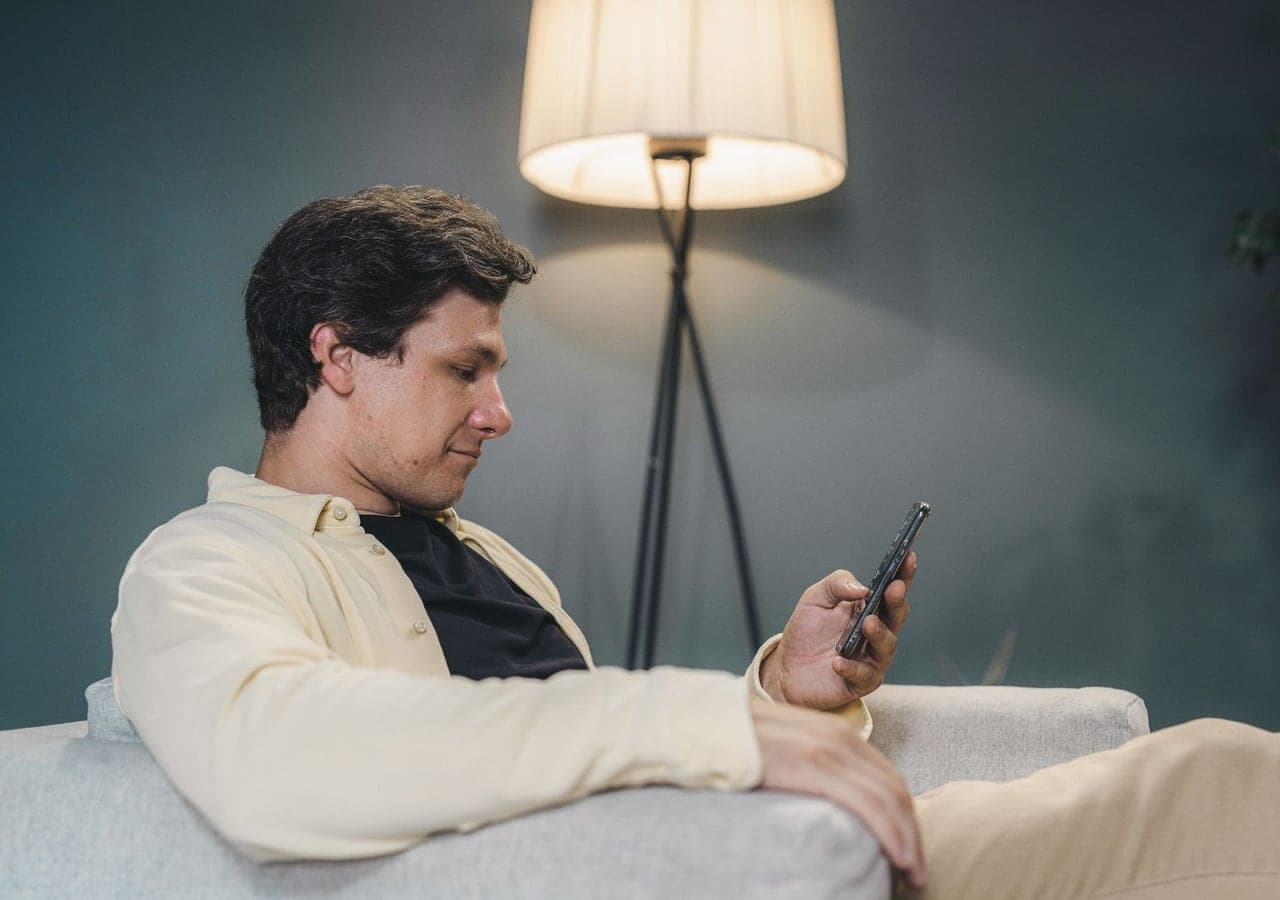 A man relaxing on a sofa while looking at his smartphone