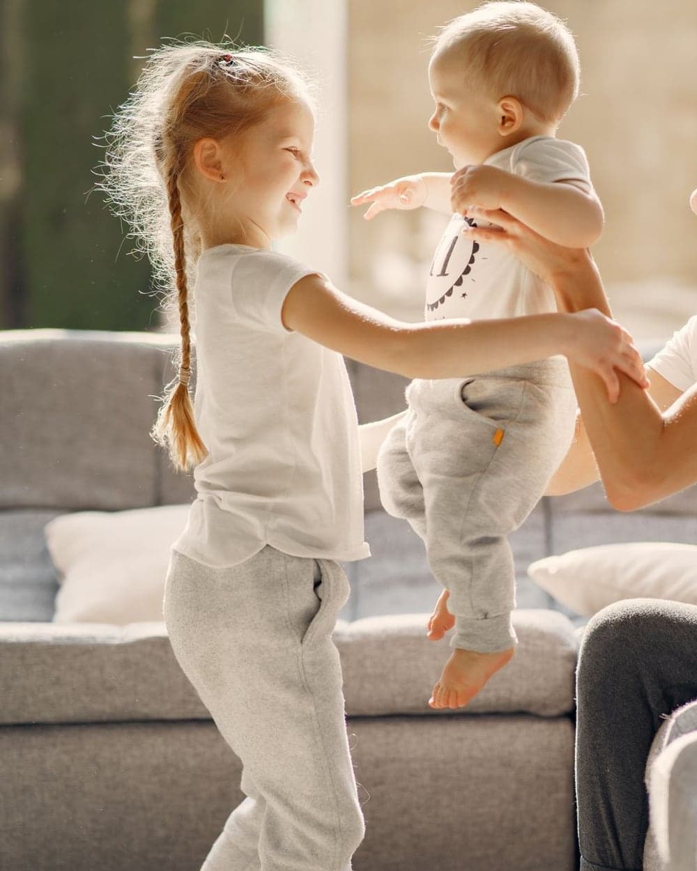 Two young children playing happily beside a sofa in a bright living room
